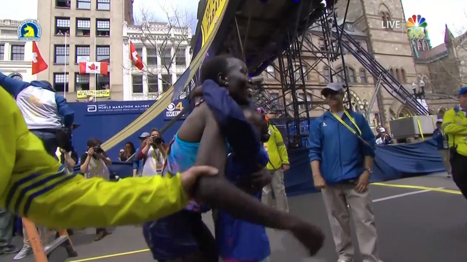 Edna Kiplagat hugs her children after being the first woman racer to cross the finish line.